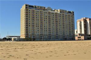 a large building on the beach next to a sandy beach at Oceanfront condo, ocean view and indoor pool in Virginia Beach