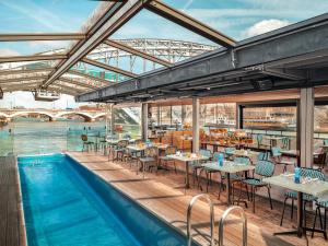 a restaurant with a pool and tables and a bridge at Hotel OFF Paris Seine in Paris