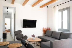 a living room with a couch and chairs and a tv at Pyrra apartments in Skiros