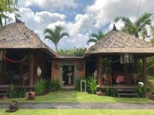 a house with two thatched cottages with grass at Ketewel Bed & Breakfast Yoga Room in Ketewel