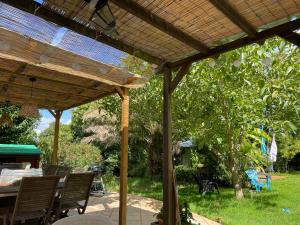 a wooden pergola with a table and chairs in a yard at Chaumière authentique in Herbignac