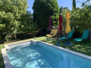 a swimming pool with two lawn chairs and umbrellas at Mas Valentine in Roquemaure +10 photos