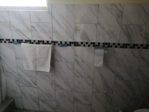 a bathroom with a towel hanging on a tiled wall at Green Haven Ecolodge Lligua in Baños +17 photos