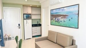 a kitchen with a couch and a painting on the wall at Flats no centro de Porto de Galinhas próximo à praia opções com e sem piscina privativa in Porto De Galinhas