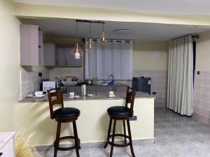 a kitchen with two bar stools and a counter at Riverside Haven in Ogembo