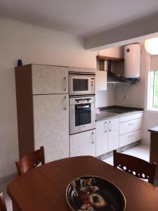 una cucina con tavolo, piano cottura e forno a microonde di Apartamentos Sardiñeiro a Fisterra (Finisterre)