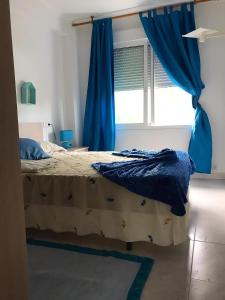 una camera da letto con un letto con tende blu e una finestra di Apartamentos Sardiñeiro a Fisterra (Finisterre)