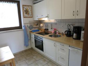 a kitchen with white cabinets and a sink at Bungalow am Osterteich in Gernrode - Harz