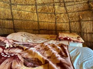 a bed with a thatched ceiling and a bedsheet at Camping Lekdushi - Shehu in Tepelenë