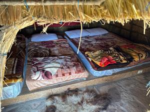 two beds in a straw hut with food on them at Camping Lekdushi - Shehu in Tepelenë
