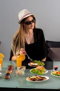 eine Frau, die mit einem Teller Essen an einem Tisch sitzt in der Unterkunft Dazzling Santorini Villa Villa Luck 2 Bedrooms Furnished Interiors in Perissa