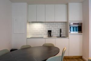 a kitchen with a table and chairs and a kitchen with white cabinets at Residentie Miguel - sea view and underground parking in Knokke-Heist