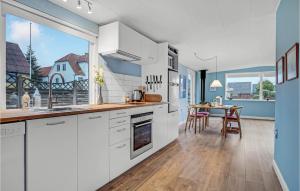 a kitchen with white cabinets and a dining table at Two-Bedroom Holiday Home In Broager in Broager