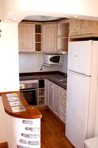 a kitchen with a white refrigerator and wooden cabinets at Bungalow con piscina 28 in Gran Alacant