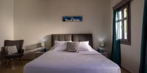 a bedroom with a bed and a chair and a window at Smaragdi in Perivolos