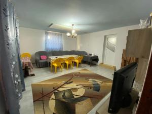 a living room with a table and yellow chairs at Vila Lacul Caldarusani in Grădiştea
