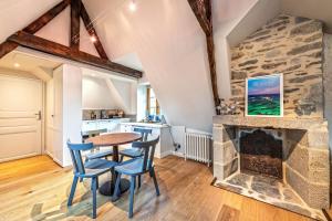 a living room with a stone fireplace and a table and chairs at Ar Barzh Kadiou III in Quimper