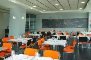 a dining room with white tables and orange chairs at Gobeo Park in Vitoria-Gasteiz