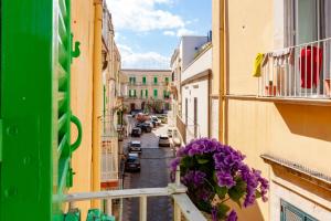 un balcone con fiori viola su una strada della città di SUD 47 a Molfetta