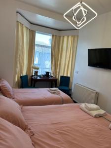 a hotel room with two beds and a television at Holland House in Great Yarmouth