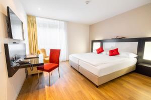 a bedroom with a bed and a desk with a red chair at Restaurant & Hotel Frohsinn in Küssnacht