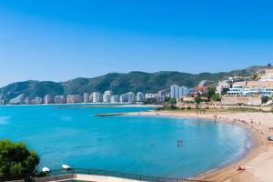 a beach with people in the water and buildings at Apartamento cerca de la playa in Cullera