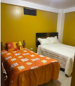 1 Schlafzimmer mit 2 Betten und einer orangefarbenen Decke in der Unterkunft D ROSSY House in Huaraz