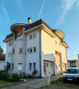 a building with a car parked in front of it at Guesthouse Jelic in Teslić