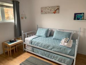 a small bedroom with a bed with blue sheets at On the Rocks Overlooking the Sea in Twillingate +9 photos