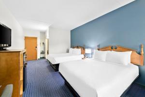 a hotel room with two beds and a flat screen tv at Clarion Inn Branson in Branson