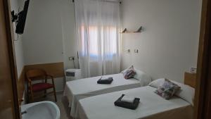 two beds in a hotel room with a sink and a mirror at Residencial Oscense in Huesca