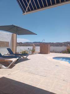 a patio with chairs and an umbrella and a pool at Bonita Casita Luz del Sol in Arboleas