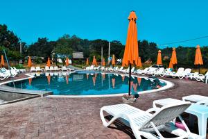 a swimming pool with white chairs and umbrellas at Casutele Bunicii in Ocna Şugatag