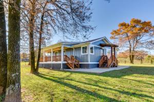 a small blue house in a field with trees at Modern Clarkesville Cottage with Decks and Patio! in Lakemont
