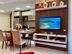 a living room with a table and a large television at Resid. Clube Mar Grosso - Laguna - LAG605 in Laguna
