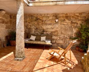 a stone room with a bench and a chair at Casa María da Reza in Ribadavia