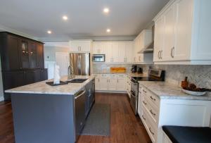 a kitchen with white cabinets and granite counter tops at Deer Run Cottage- Golf Course cottage in Kawartha Lakes +15 photos
