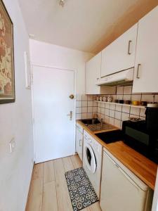 a kitchen with a washer and a white door at piscine, parking, vue mer, 23 m2 in Saint-Tropez