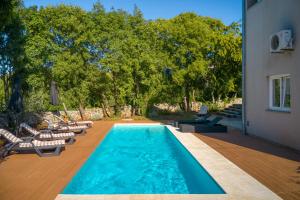 a swimming pool with lounge chairs and a house at Modern Villa Krk in Gabonjin