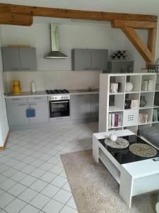 a kitchen with white cabinets and a white tiled floor at FeWo Mecklenburgische Schweiz in Groß Roge