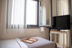 a room with a bed and a tv and a window at Sea La Vie in Agia Marina Aegina