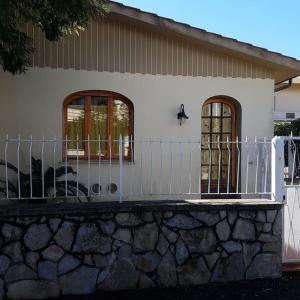 a white house with a fence and a stone wall at La casina - Castiglioncello in Castiglioncello