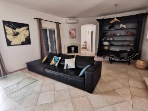 a black leather couch in a living room with a fireplace at Le Loriot in Auriol