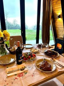 a wooden table with plates of food and wine glasses at Vila Alpine Arlon Gjinar in Gjinar +75 photos