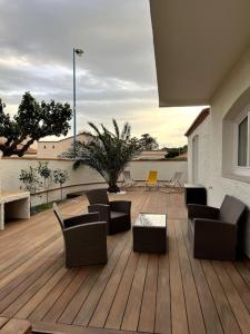 a wooden deck with chairs and tables on a building at La Villa du Soleil in Saint-Cyprien
