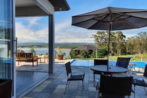 een terras met een tafel, stoelen en een parasol bij Mirante Mar de Minas - Casa para Temporada Lago de Furnas pertinho dos Canyons in São José da Barra