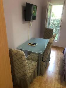 a dining room table with chairs and a television at Apartmani Milanovic Susanj in Bar