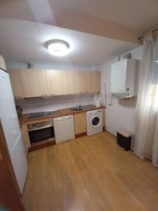 Una cocina con electrodomésticos blancos y suelo de madera. en Calle San Pablo, en Zaragoza