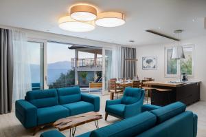 a living room with blue couches and a dining room at Villa Luna Mare mit Pool und Sauna in Podaca