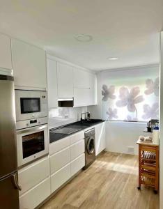a kitchen with white cabinets and a washer and dryer at Acogedora casa recién reformada con jardín y wifi in Laredo